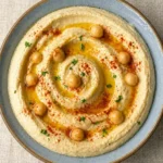 Homemade hummus in a glass jar with olive oil drizzle