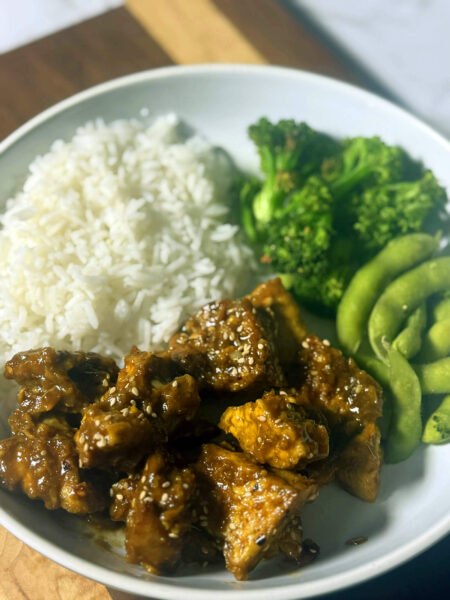 Crispy orange tofu bowl with edamame rice, broccoli and sesame seeds