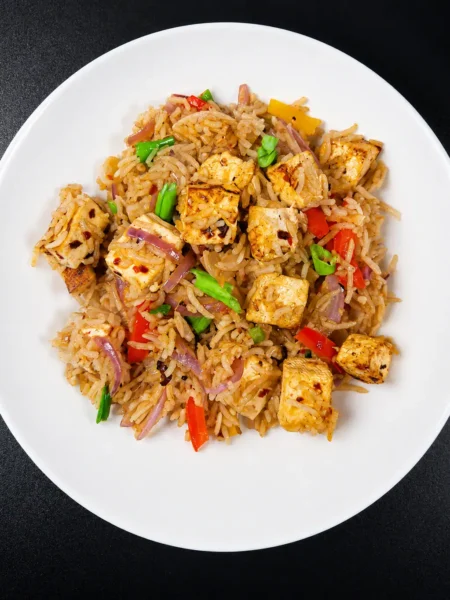 Paneer fried rice in a cast iron wok with green onion garnish