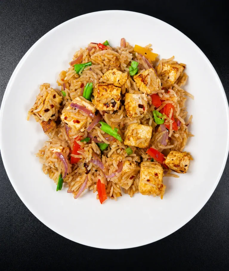 Paneer fried rice in a cast iron wok with green onion garnish
